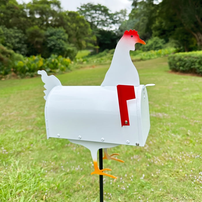 White rooster mailbox on a ground stake in a farm yard